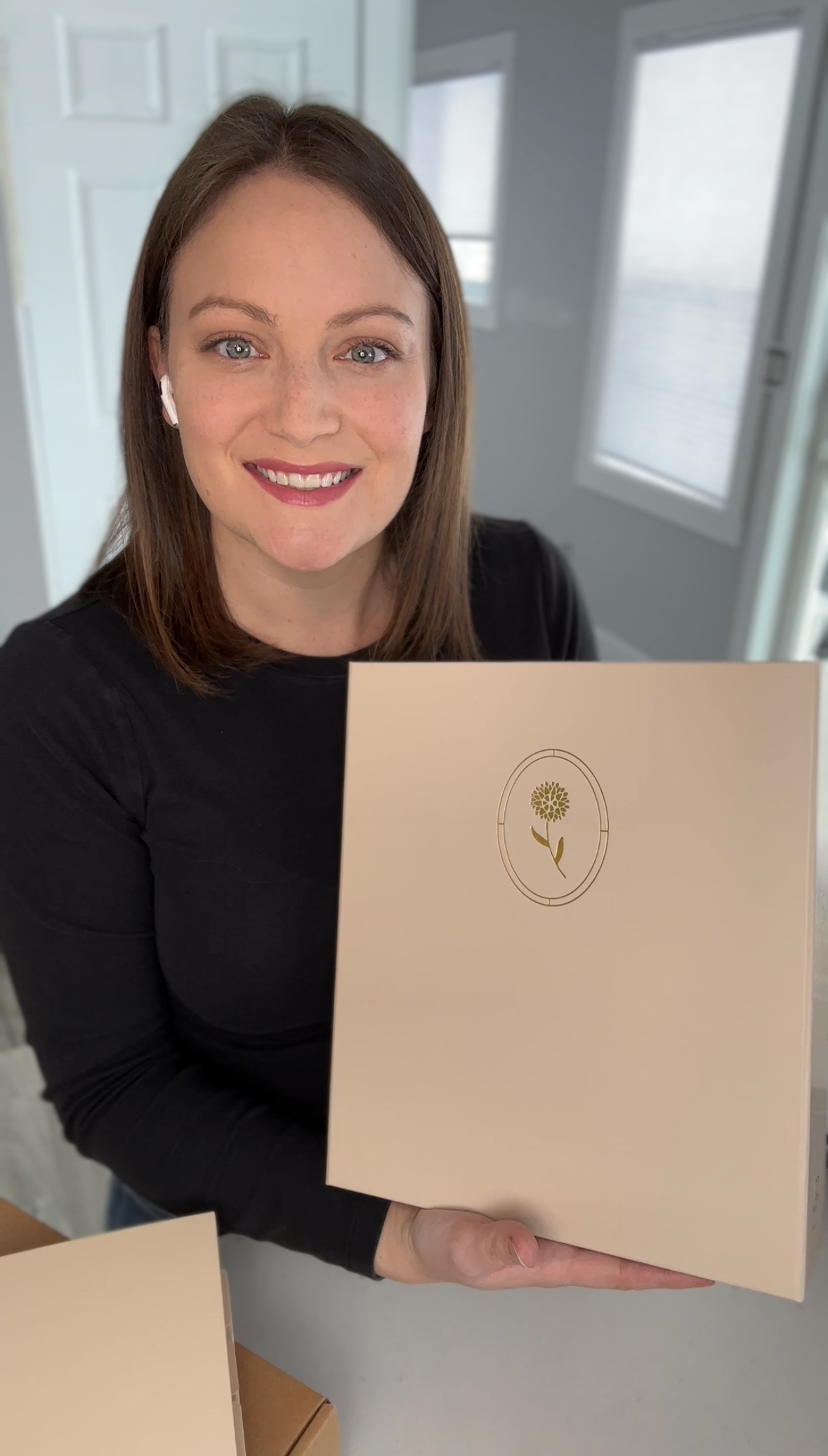 Lia, Dahlia's Founder, holding the Journal Capsule standing in a room with white walls and a door.